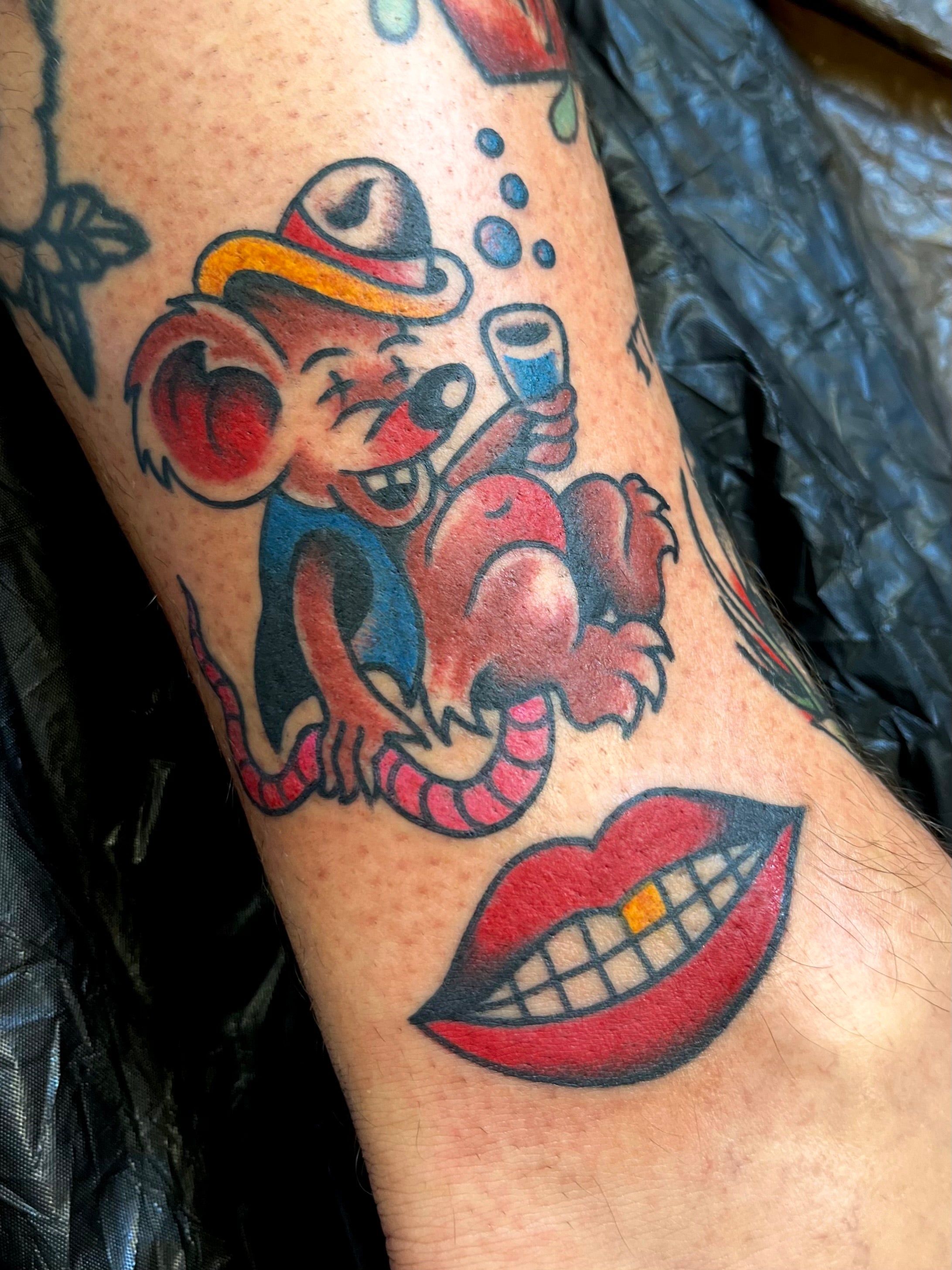 Colourful Bold American traditional classic drunk rat tattoo with a rosie camanga smiling mouth. Tattooed in London.