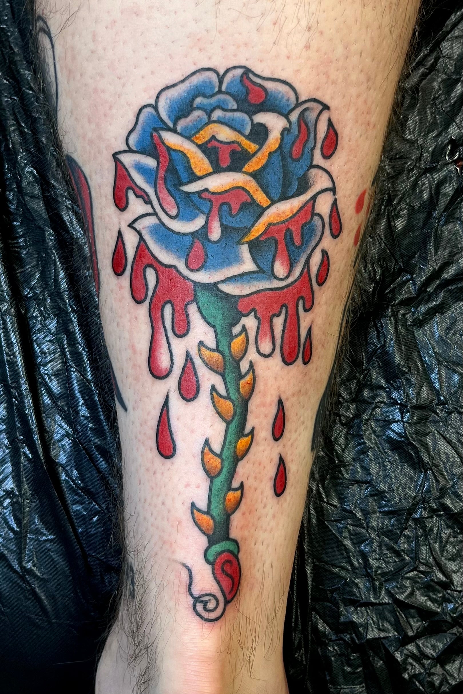 Colourful Bold American traditional classic single stem rose tattoo dripping with blood. Tattooed in London