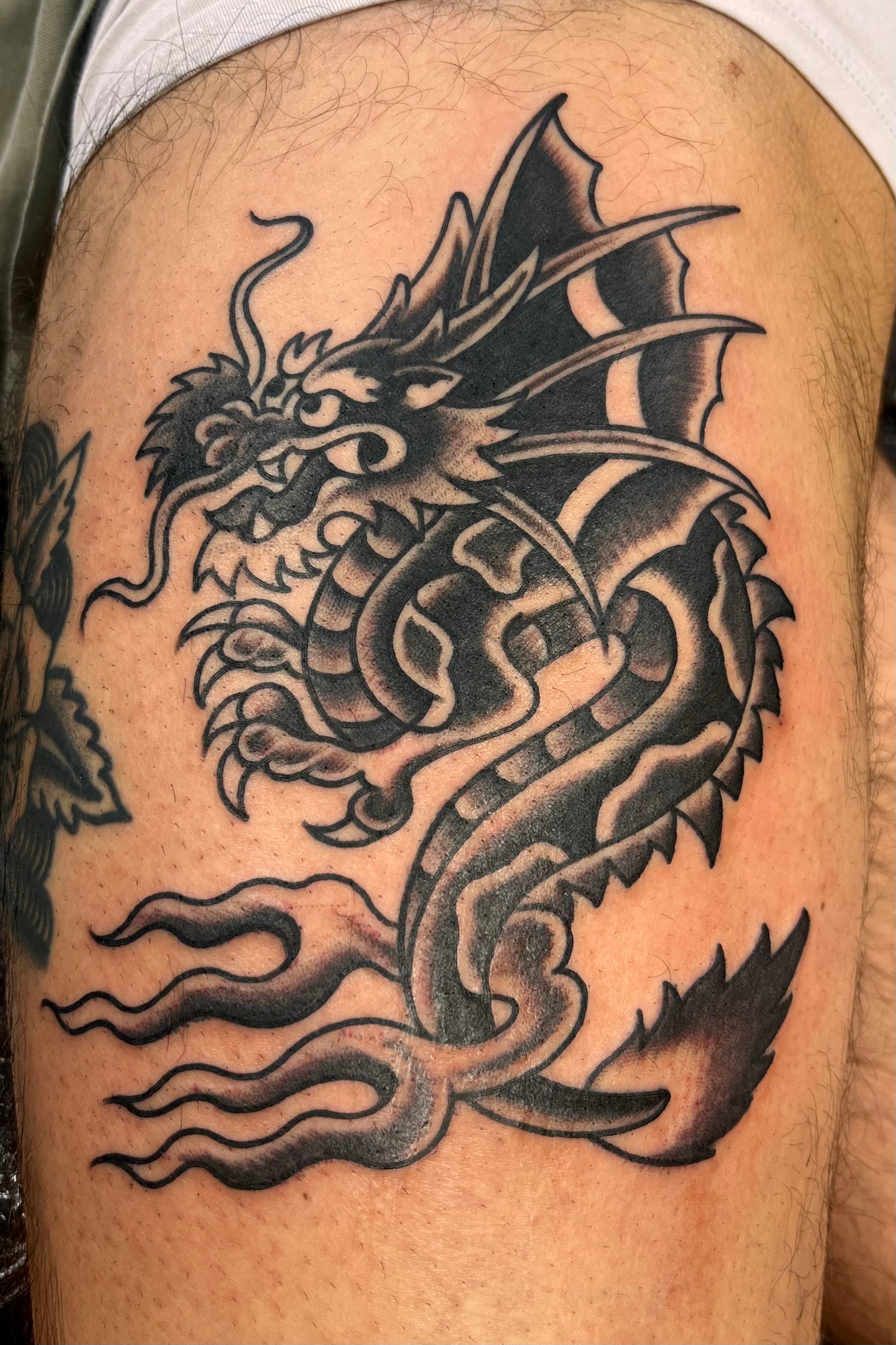 Black and grey Bold American traditional classic sailor jerry winged dragon tattoo on the thigh, tattooed in london at frith street tattoo