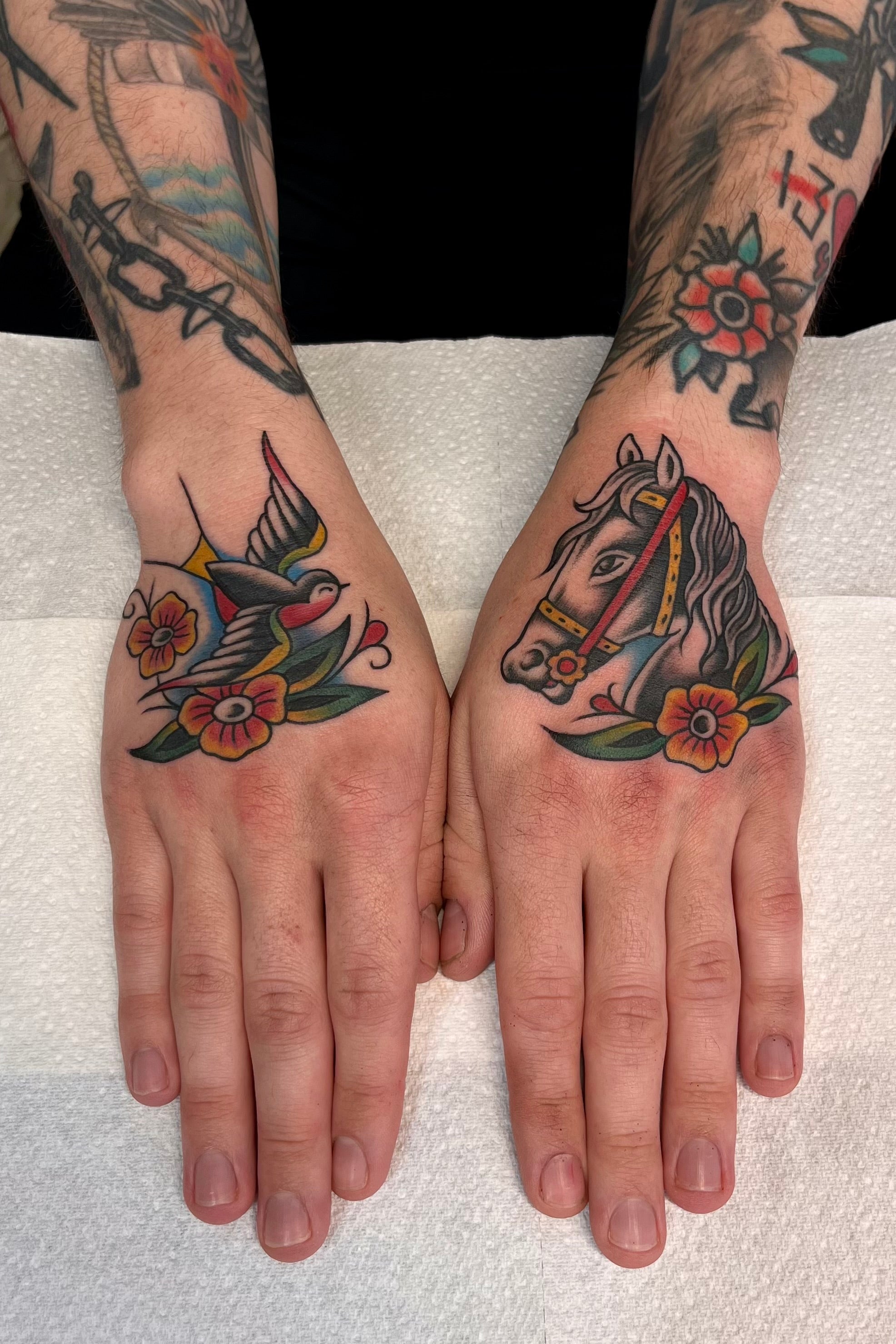 Bold American traditional classic hand tattoos of a swallow with flowers, and a horse head with flowers. Tattooed in London