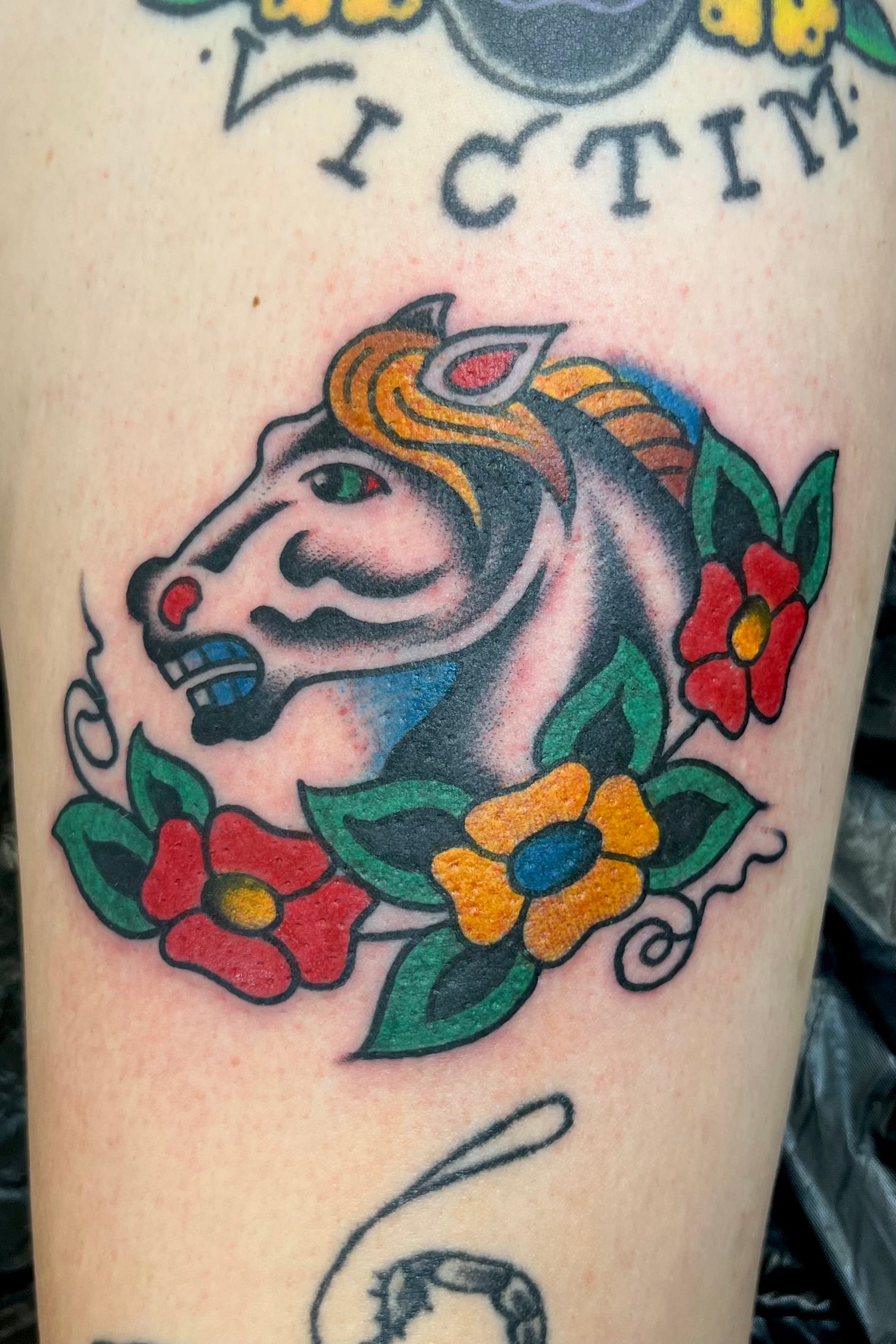 Colourful Bold American traditional classic spaulding and rogers horse head tattoo with flowers. Tattooed in London.