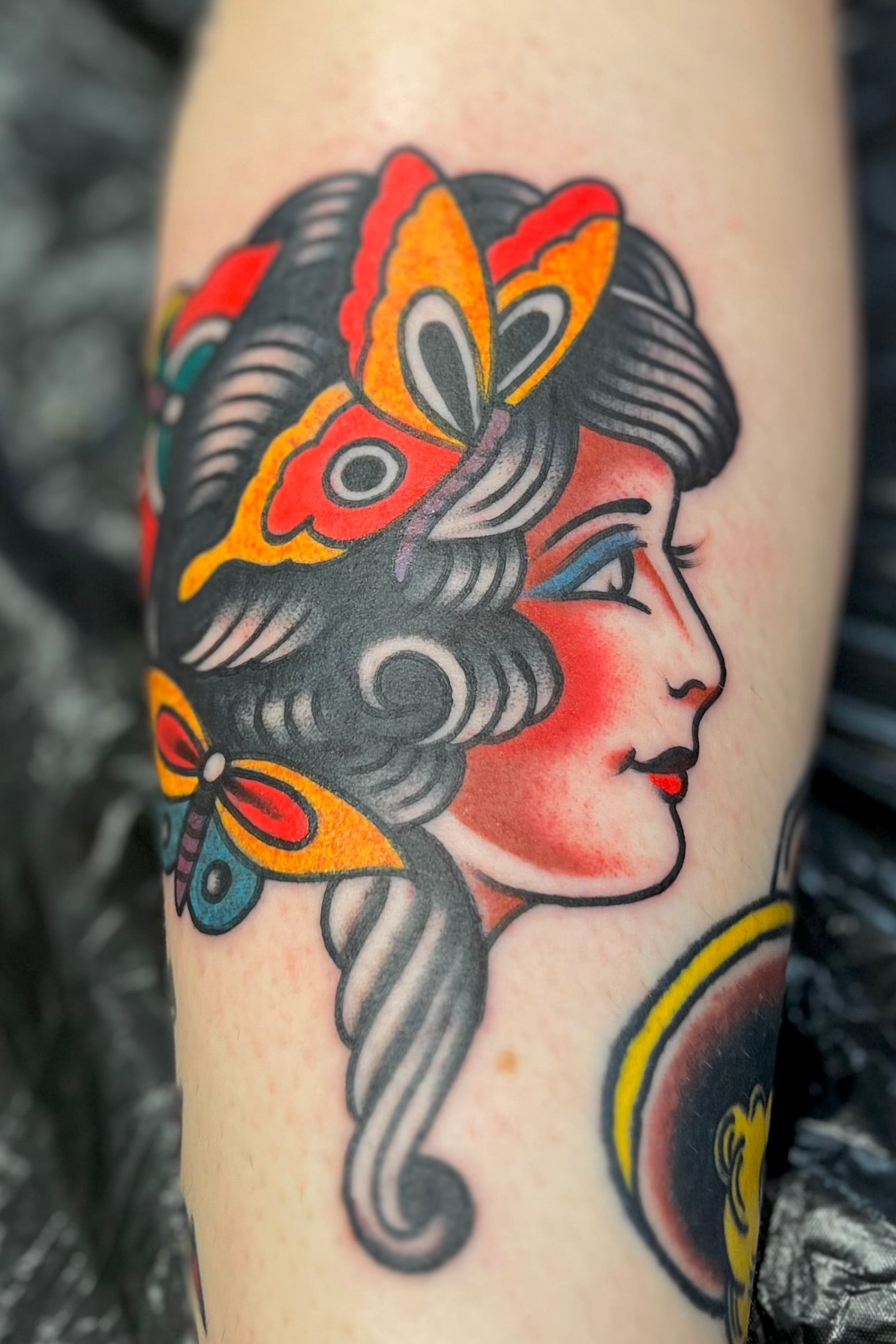 Bold American traditional classic Cap Coleman girl head tattoo with butterflies in her hair in colour. Done in London by jake cordal at frith street tattoo