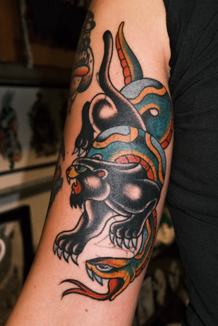a bold american traditional blast over tattoo of a crawling panther and a snake, full colour. by jake cordal at frith street tattoo 