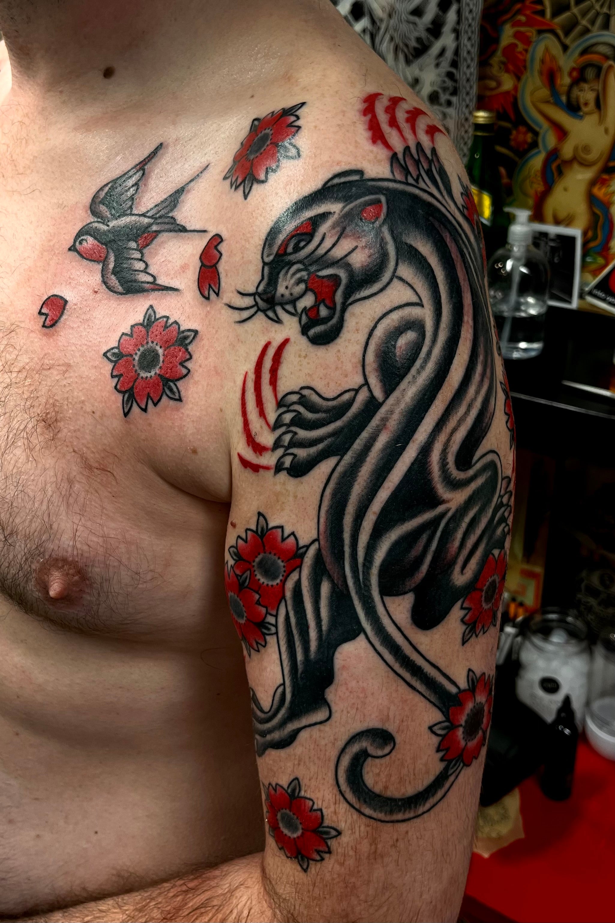 Black and grey with red Bold American traditional classic panther half sleeve with cherry blossom background and a swallow on the chest. Tattooed in London.