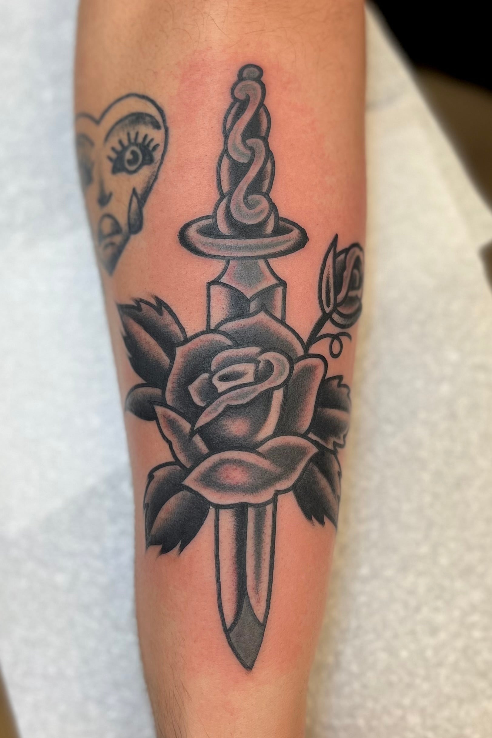 Black and grey Bold American traditional classic rose and dagger tattoo. Tattooed in London.