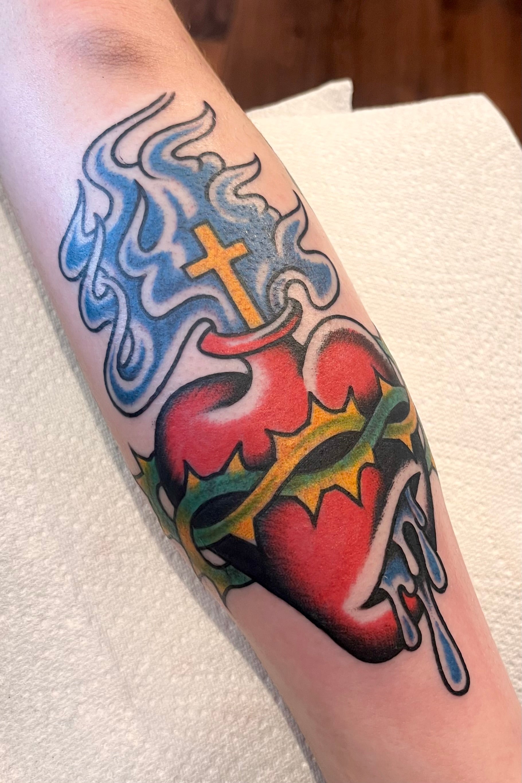 Colourful Bold American traditional classic sacred heart tattoo with blue japanese style flames. Tattooed in London.