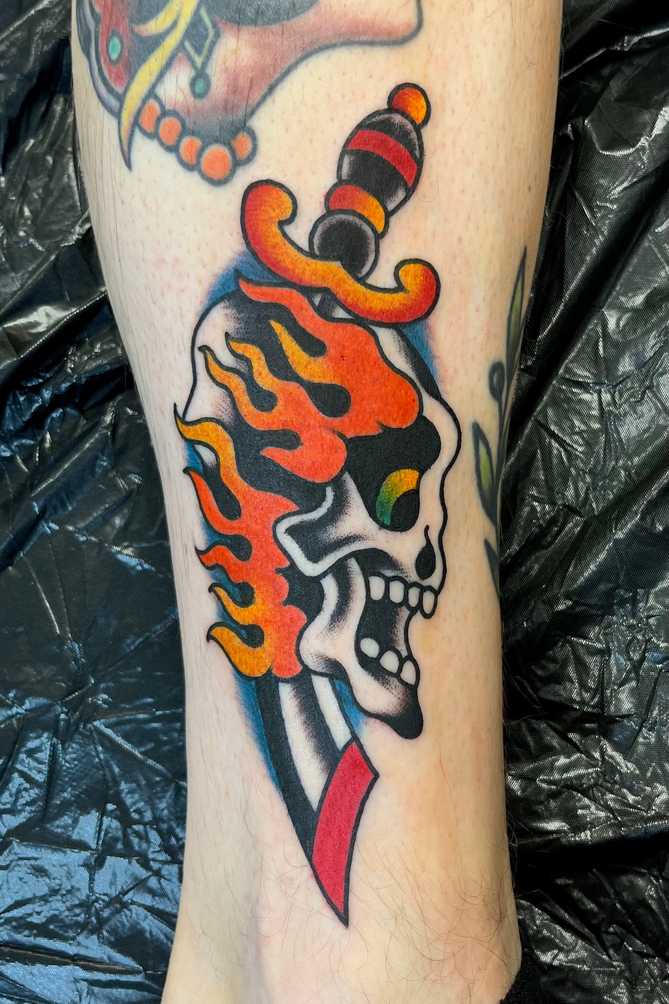 bold american traditional skull and dagger tattoo with flames in full colour tattooed in london at frith street tattoo