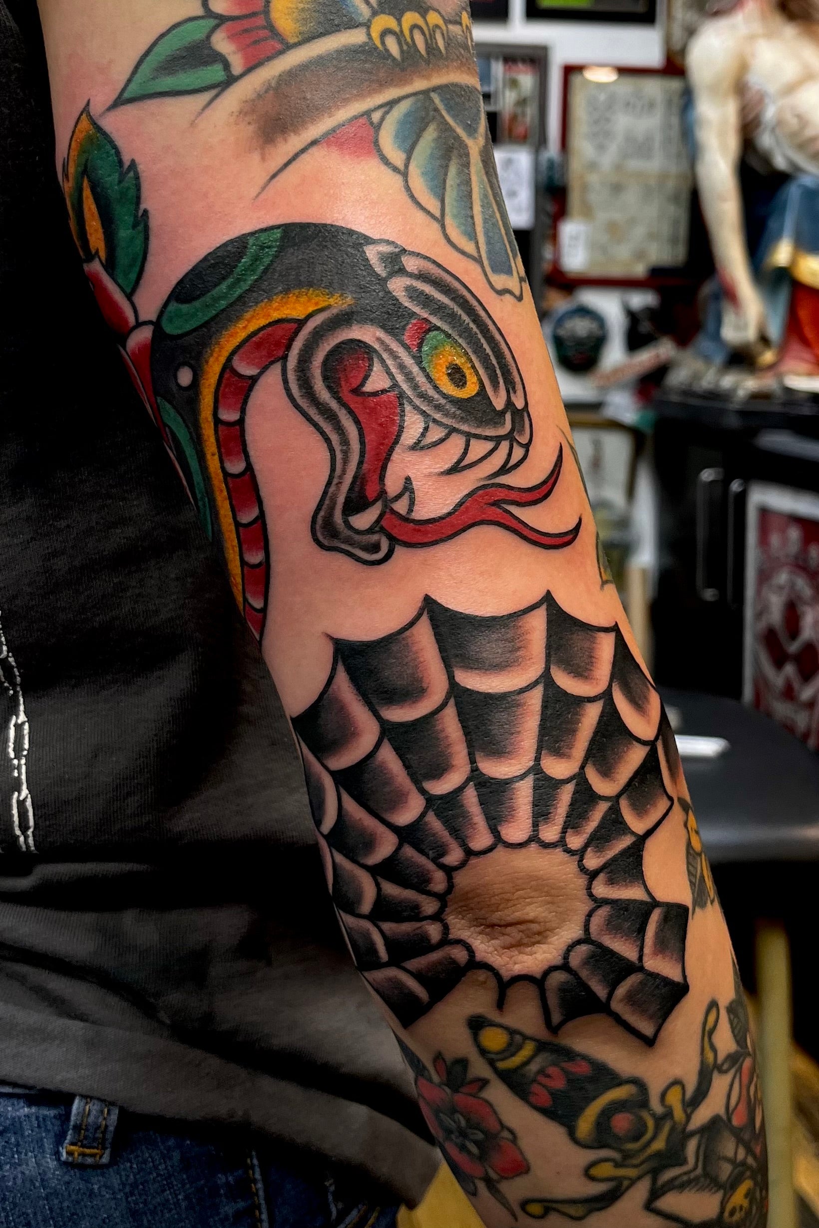 Colourful Bold American traditional classic snake head tattoo and webbed elbow gap filler. Tattooed in London.