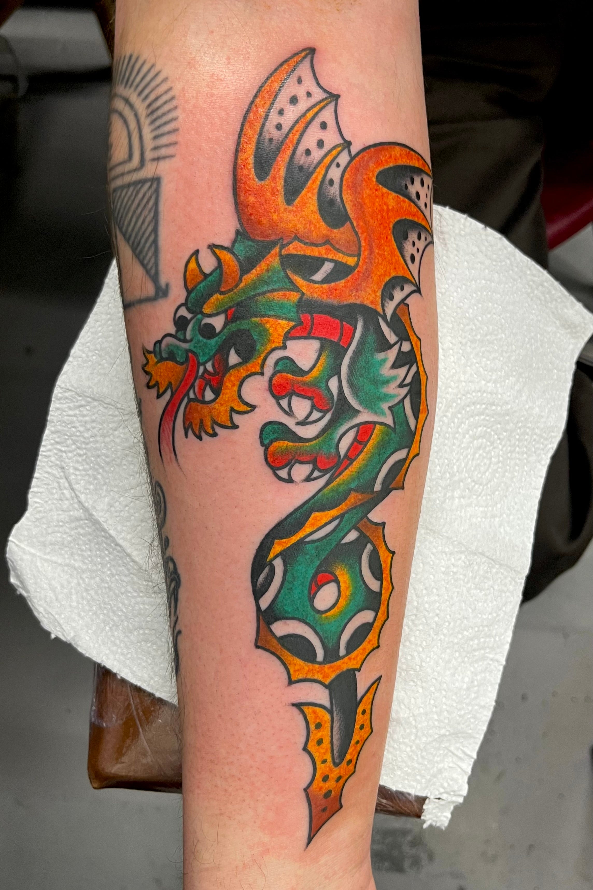 a bold american traditional dragon tattoo in full colour on the forearm. tattooed in london at frith street tattoo.