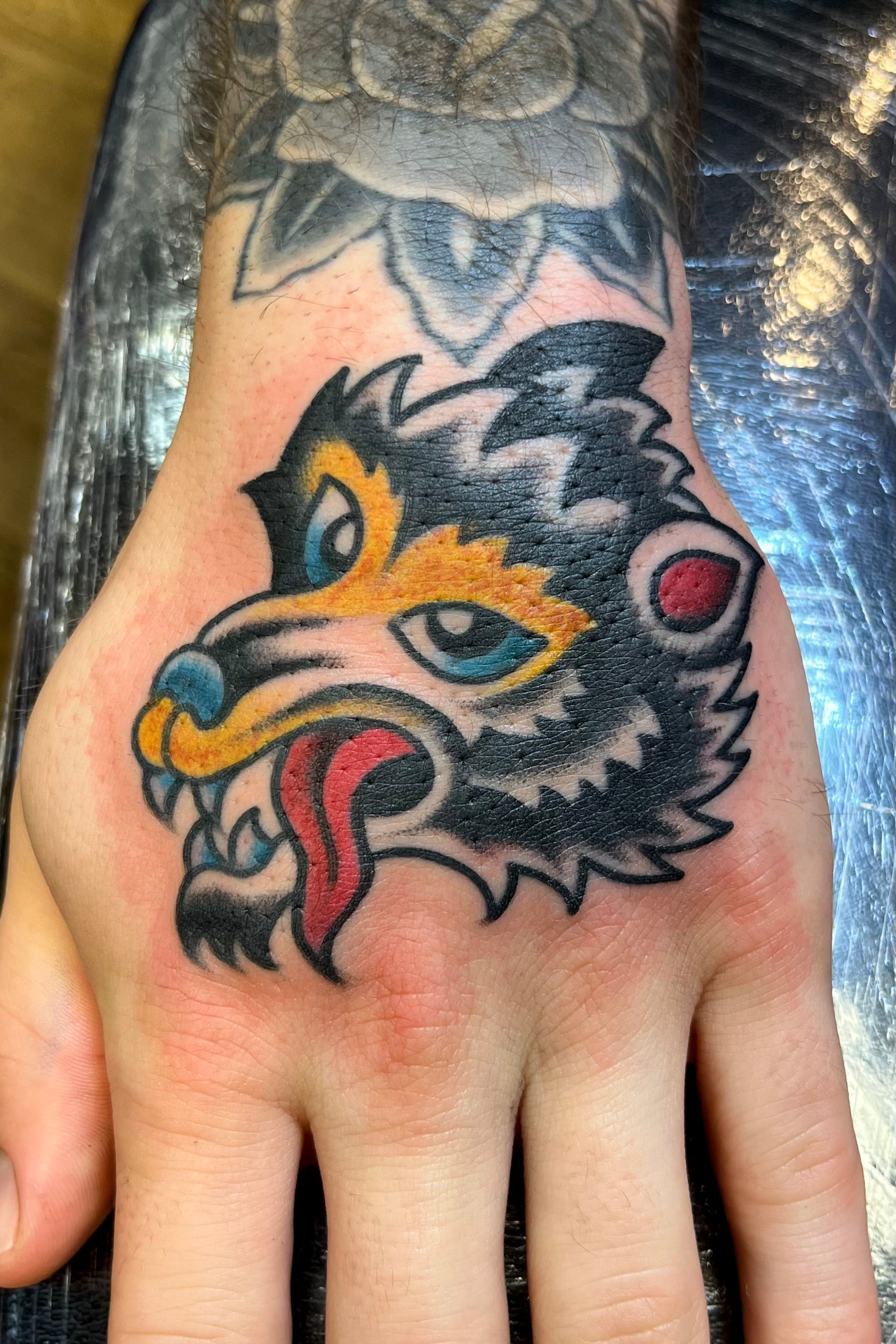 Bold American traditional classic Sailor Jerry wolf head hand tattoo in colour. Tattooed in London